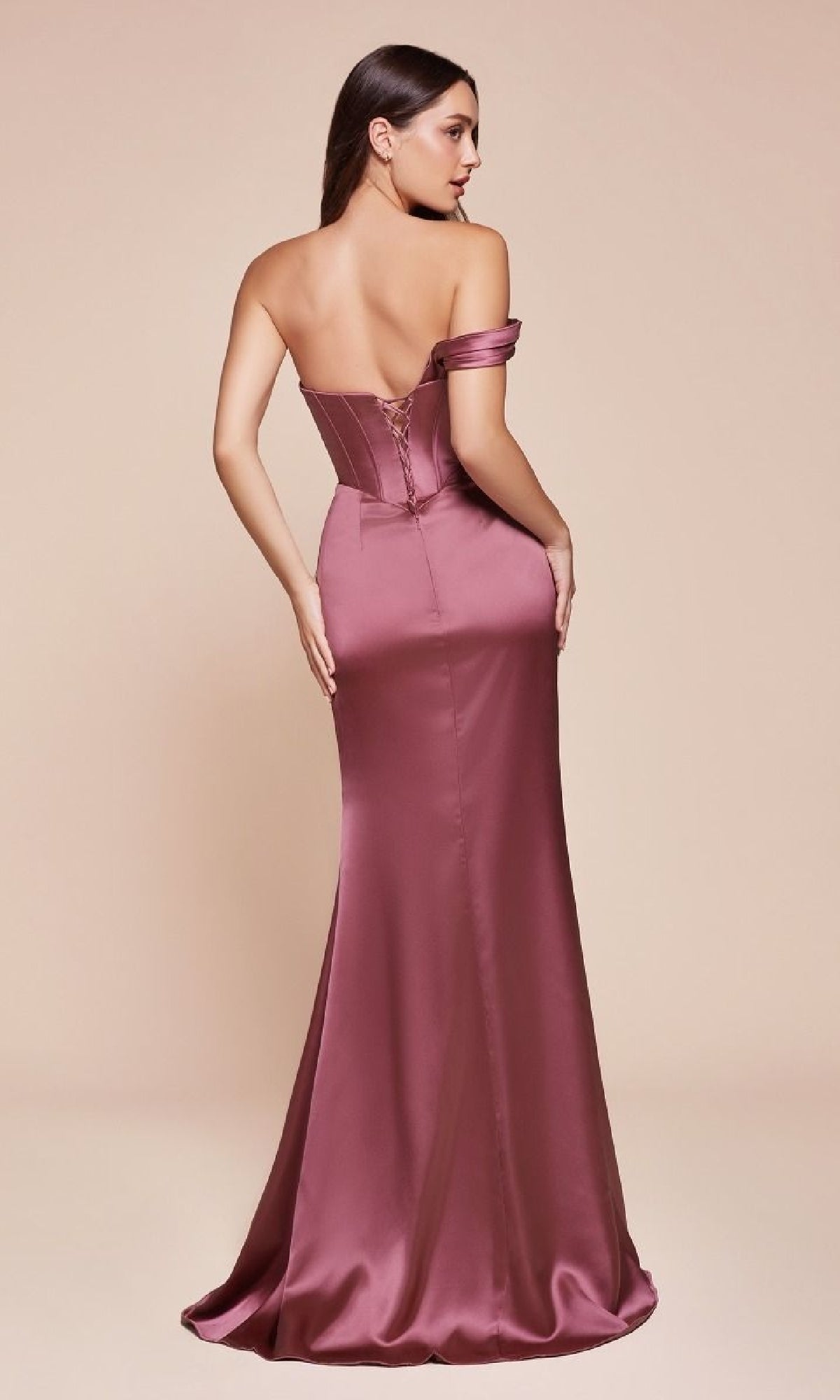 A woman stands facing away in the One-Strap Long Satin Prom Dress: Ladivine 7448, a rose-colored gown with a fitted bodice and slight train, set against a plain backdrop.